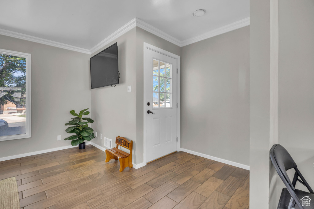 Entrance foyer with healthy amount of natural light, wood finished floors, and crown molding