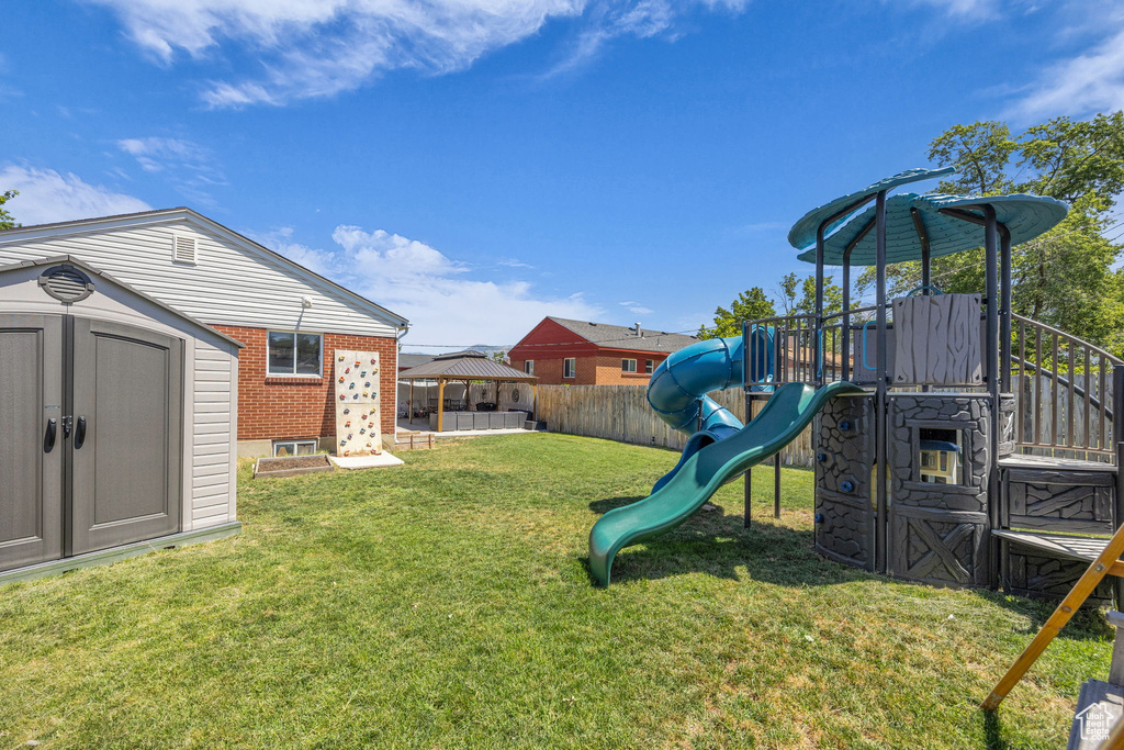 Fenced backyard with a storage shed, a gazebo, and a playground