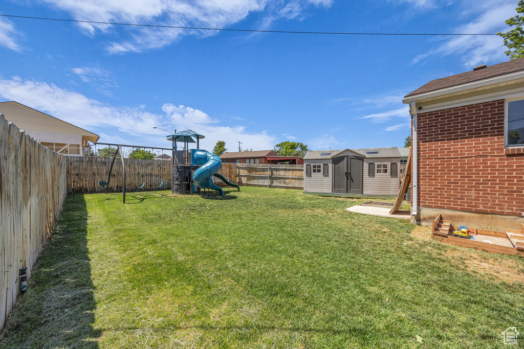 Fenced backyard featuring a playground and a shed