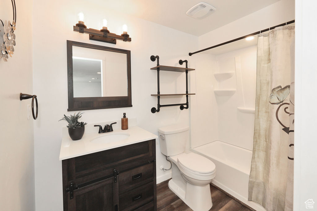 Full bathroom with vanity, wood finished floors, and shower / bath combo with shower curtain