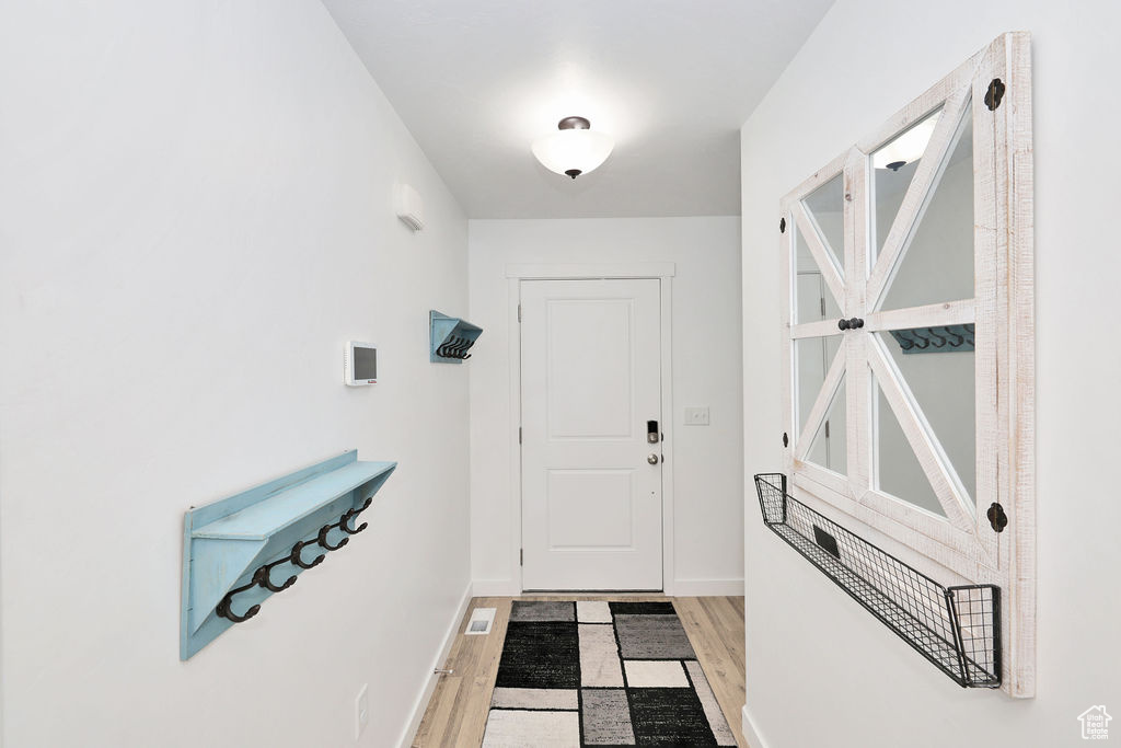 Doorway with wood finished floors and baseboards