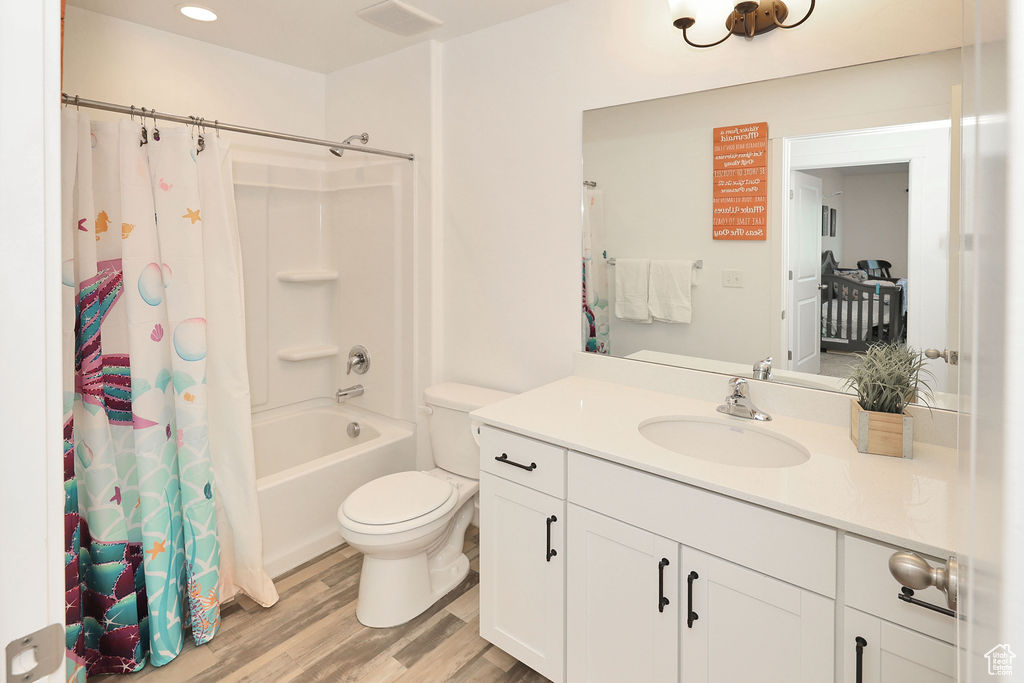 Bathroom with vanity, wood finished floors, shower / bath combo, and recessed lighting