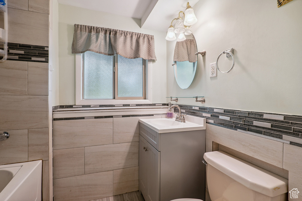 Bathroom featuring tile walls, vanity, a wainscoted wall, and bathing tub / shower combination
