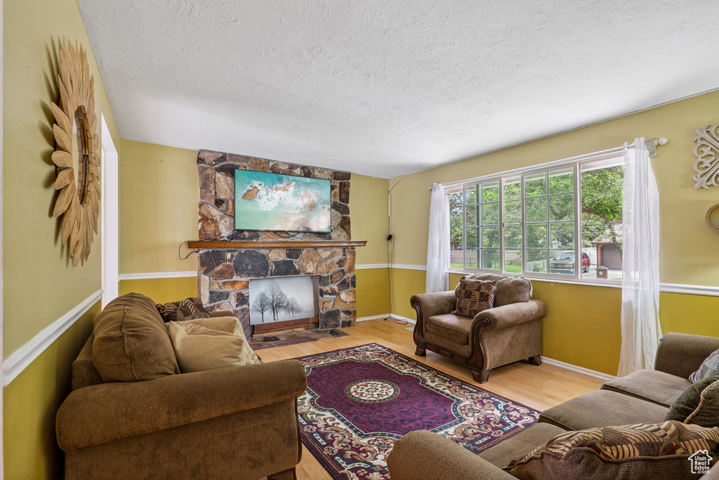 Living room with a textured ceiling, wood finished floors, and a fireplace