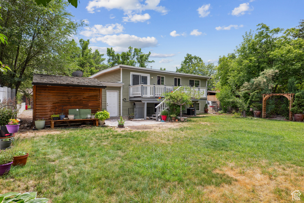 Back of property with a deck, a lawn, and stairs