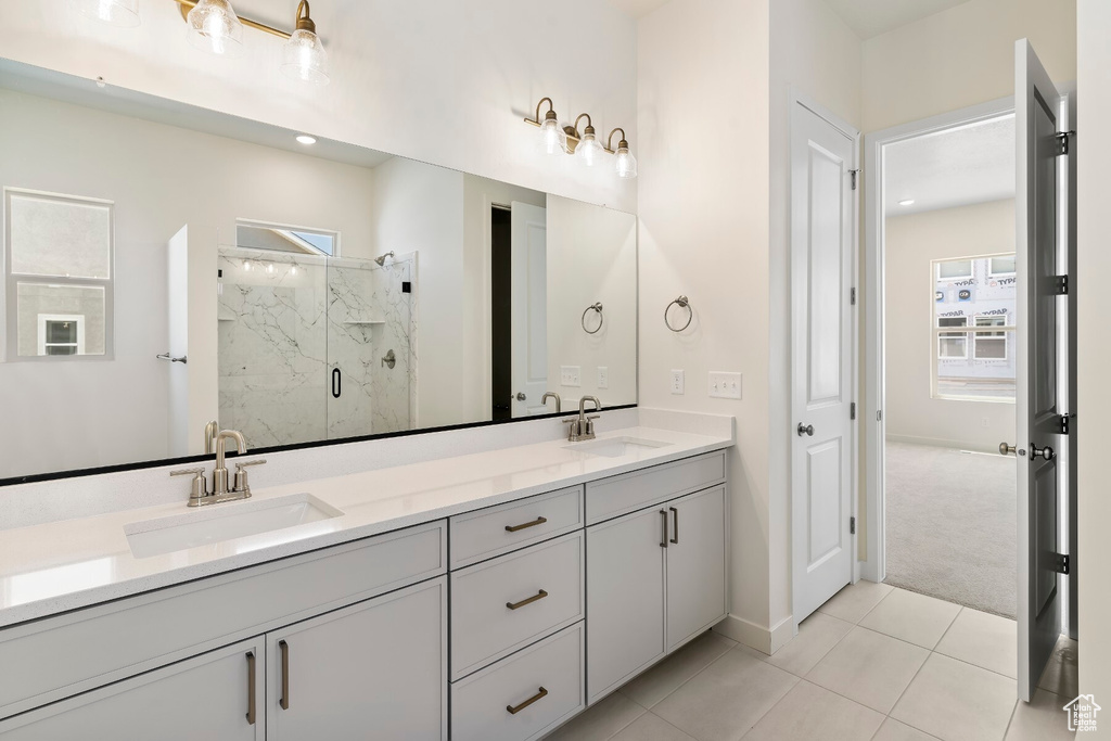 Bathroom with double vanity, a marble finish shower, and tile patterned floors