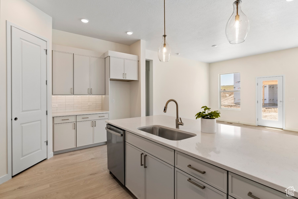 Kitchen featuring stainless steel dishwasher, pendant lighting, light wood finished floors, backsplash, and recessed lighting
