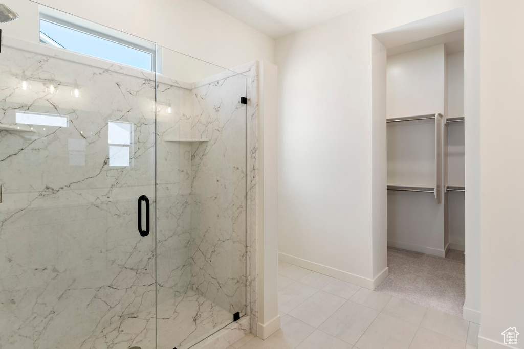 Bathroom featuring a marble finish shower and a spacious closet