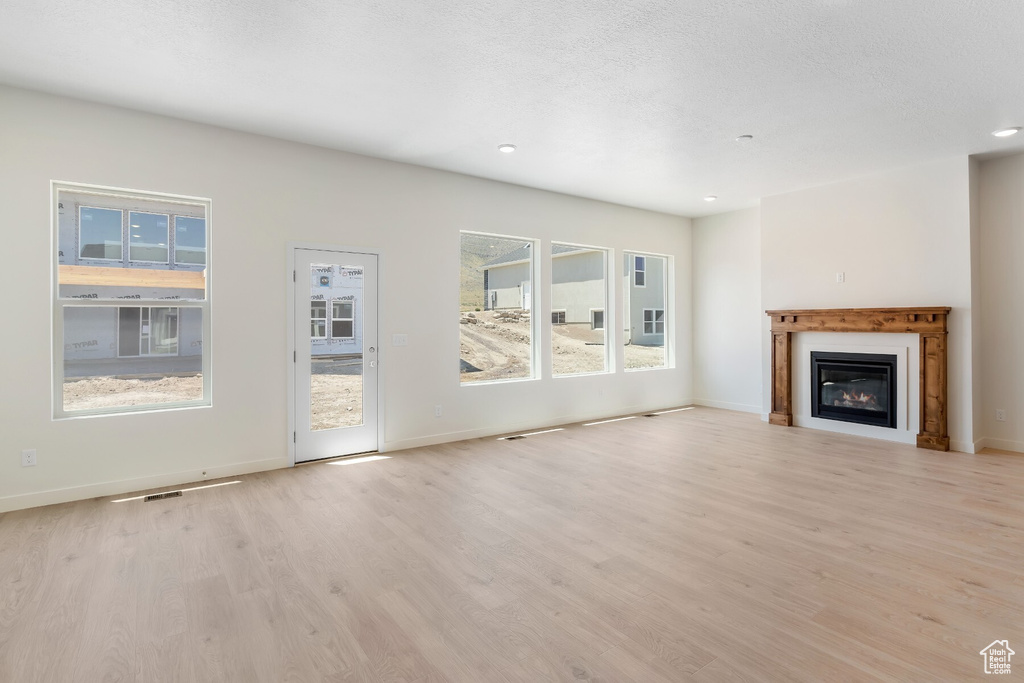 Unfurnished living room with light wood finished floors, recessed lighting, and a glass covered fireplace