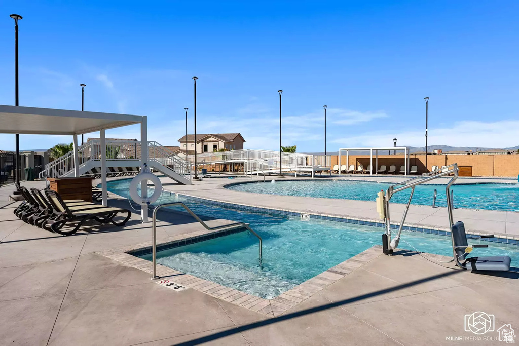 Community pool with a patio, stairway, and a jacuzzi