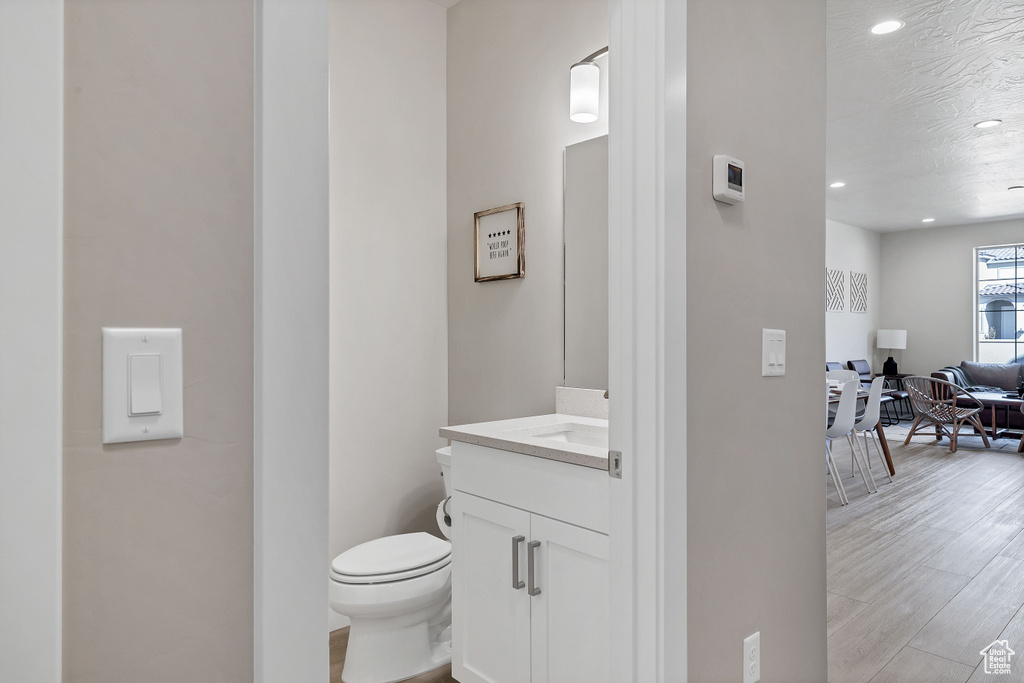 Half bathroom with vanity, recessed lighting, and wood finished floors