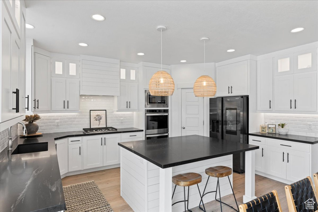 Kitchen with stainless steel appliances, dark countertops, backsplash, glass insert cabinets, and recessed lighting