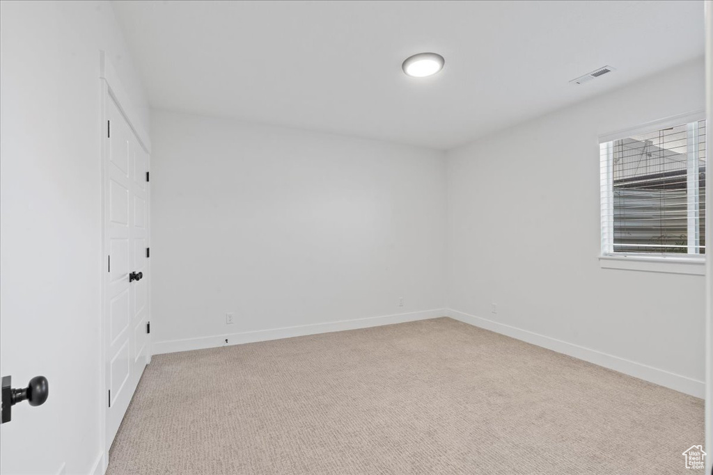 Empty room featuring light carpet and baseboards