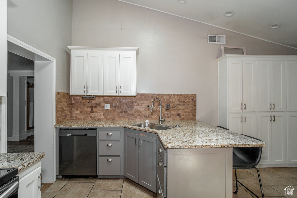 Kitchen with dishwasher, vaulted ceiling, tasteful backsplash, gray cabinetry, and a kitchen breakfast bar