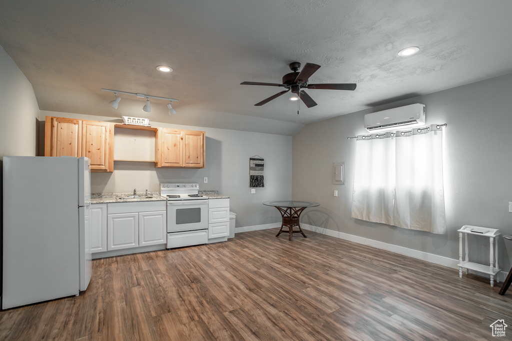 Kitchen featuring white appliances, a wall mounted AC, dark wood-style flooring, a ceiling fan, and light brown cabinetry