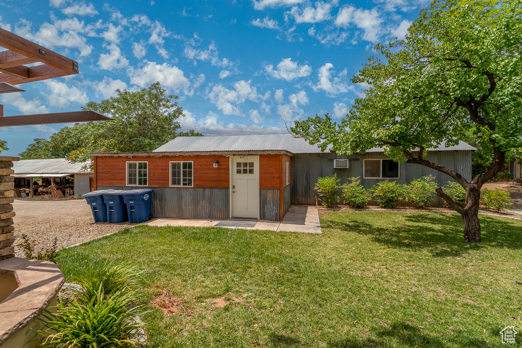 Rear view of house featuring a yard and a metal roof