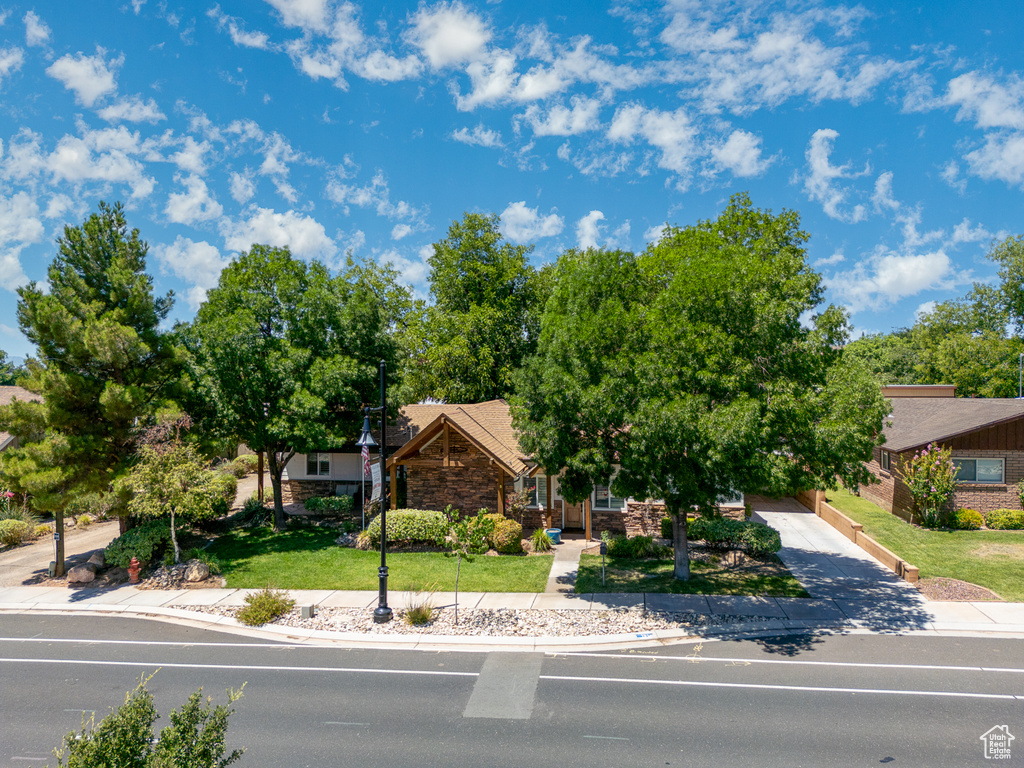 View of front of house with stone siding, driveway, and a front yard