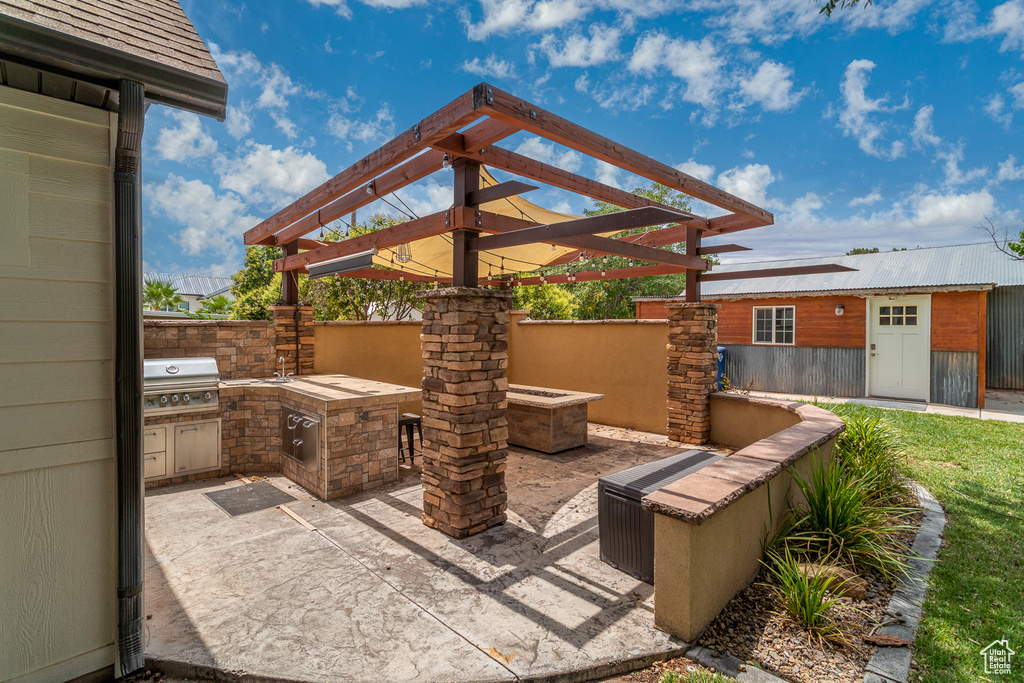 View of patio featuring exterior kitchen and a pergola