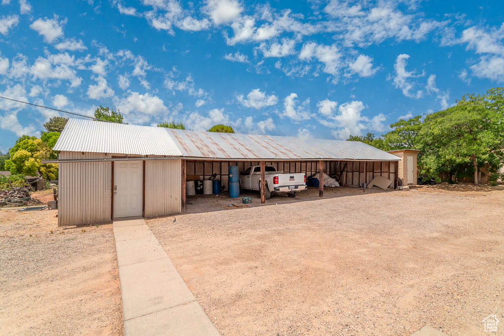 Garage with dirt driveway and a detached carport