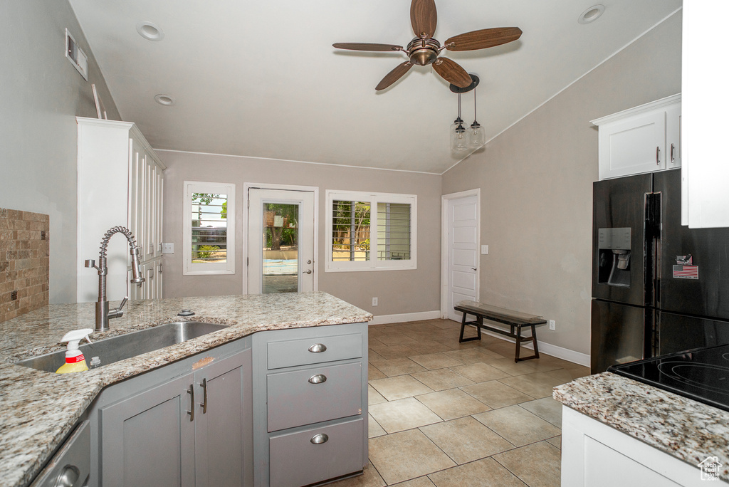 Kitchen with black appliances, ceiling fan, lofted ceiling, light stone countertops, and white cabinetry