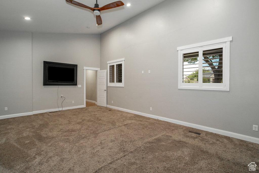 Unfurnished living room with carpet floors, a ceiling fan, recessed lighting, and a high ceiling