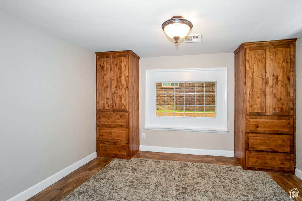 Spare room featuring dark wood-style flooring and baseboards