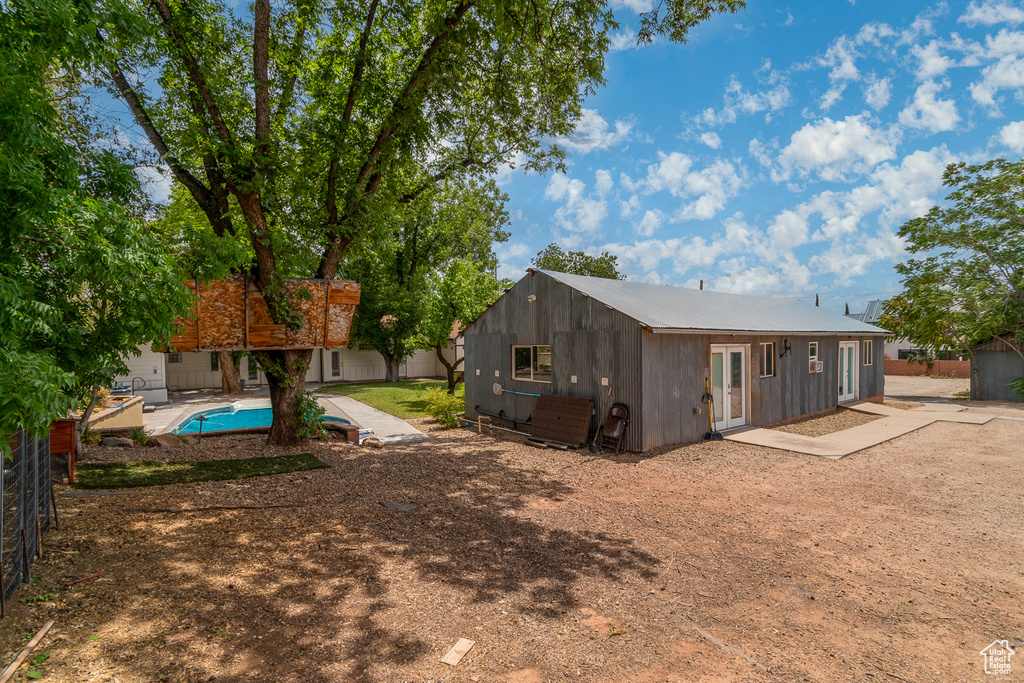 Rear view of property with an outdoor structure, a patio area, and a metal roof