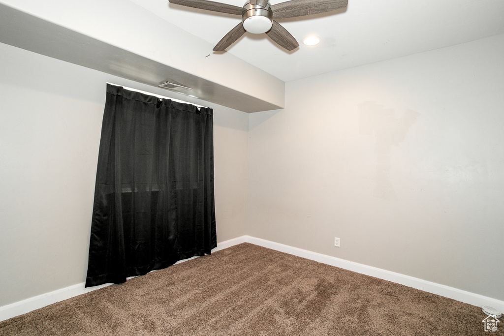 Carpeted empty room with ceiling fan and baseboards