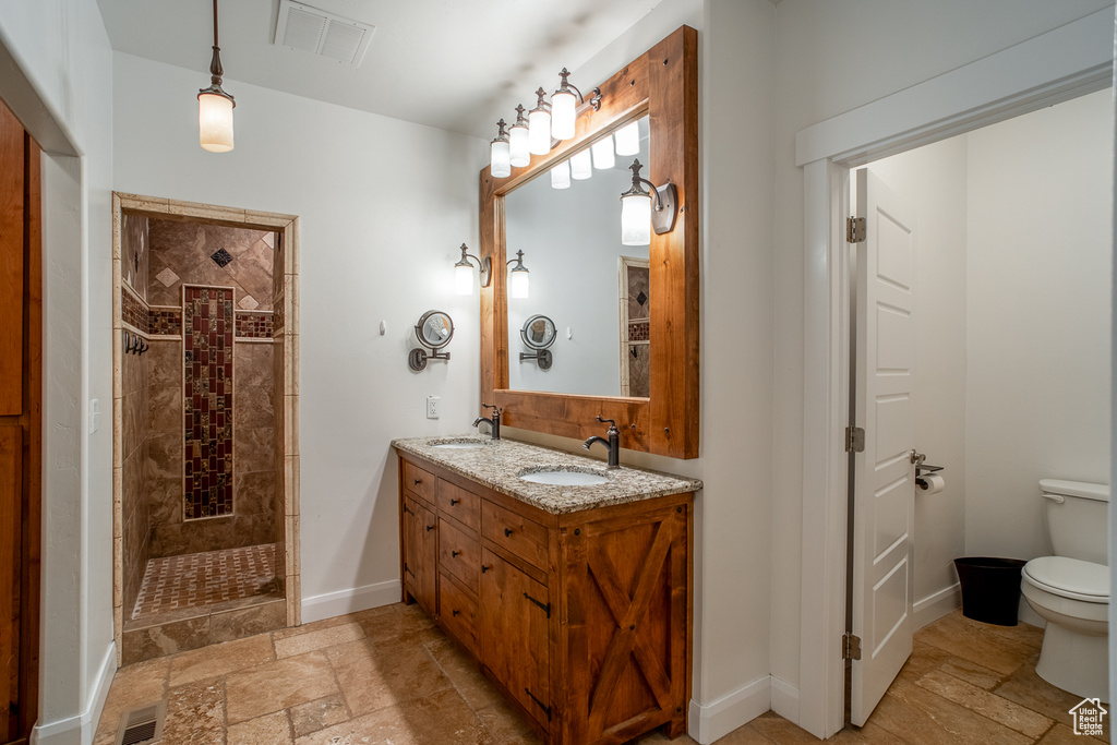 Full bathroom with stone tile floors, double vanity, and a walk in shower