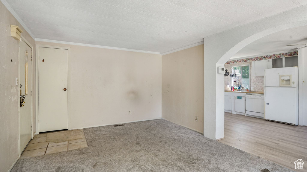 Carpeted empty room with arched walkways and crown molding