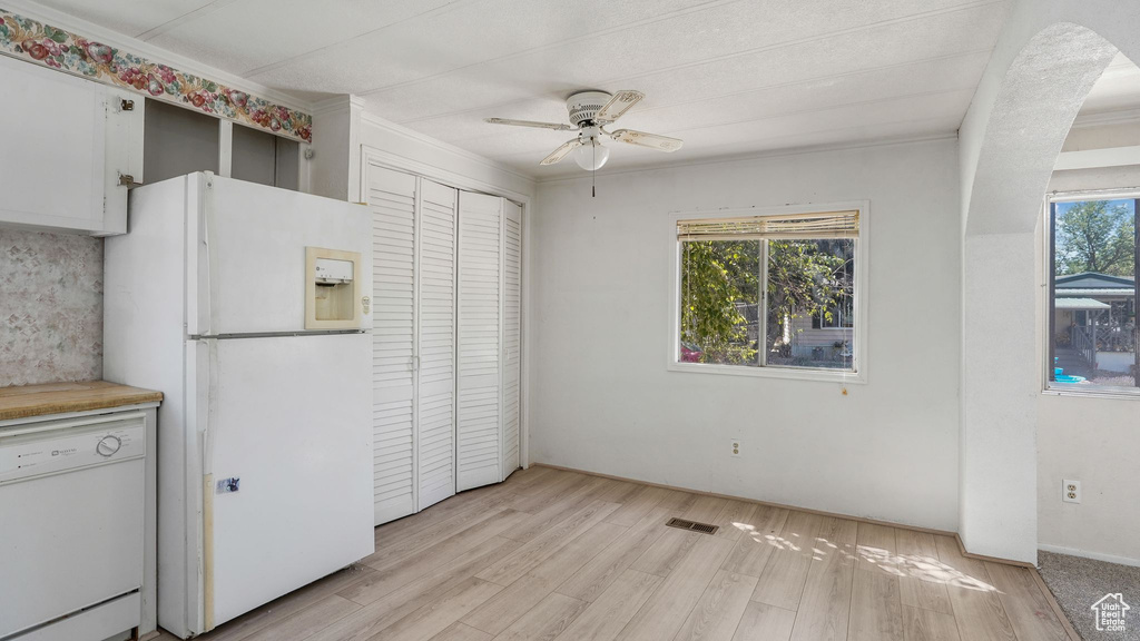 Kitchen with white appliances, a ceiling fan, light wood finished floors, crown molding, and light countertops