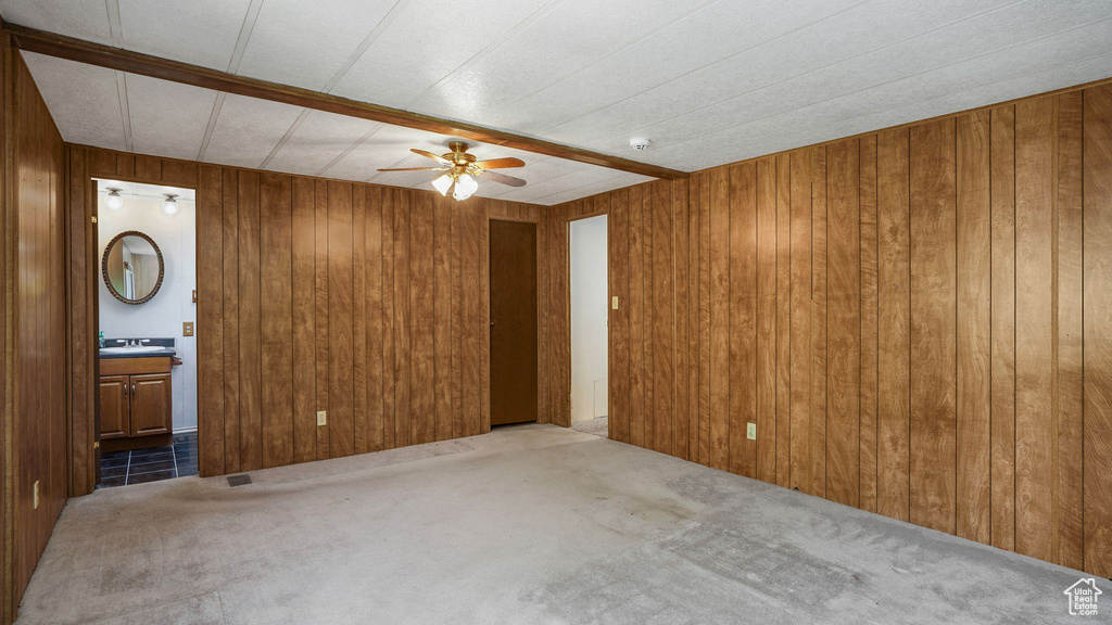 Carpeted spare room featuring a ceiling fan, wooden walls, and a smoke detector