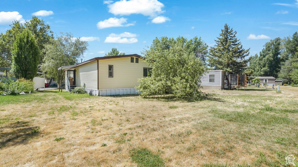 Back of house featuring a trampoline and a yard