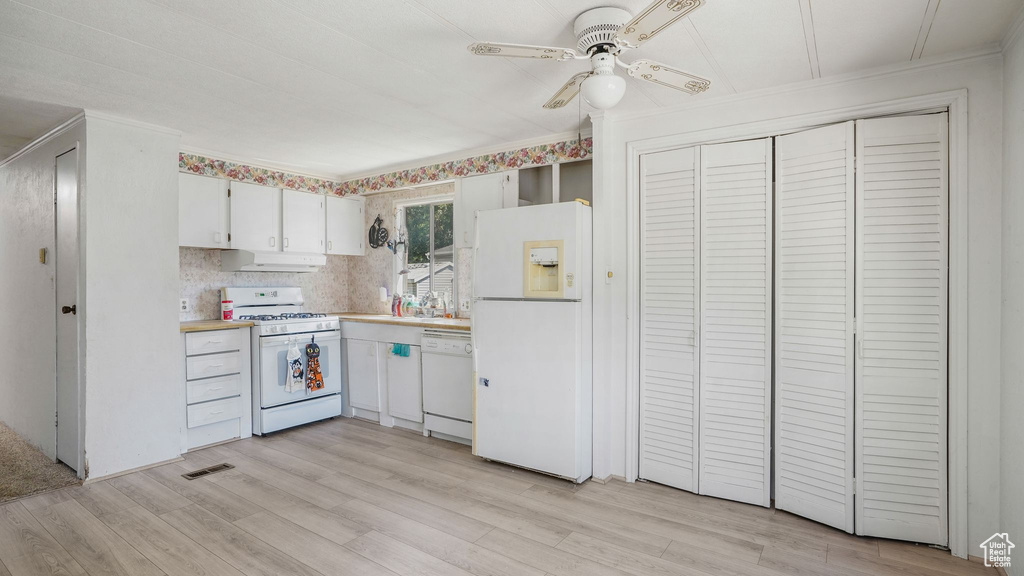 Kitchen with white appliances, under cabinet range hood, ceiling fan, light countertops, and light wood finished floors