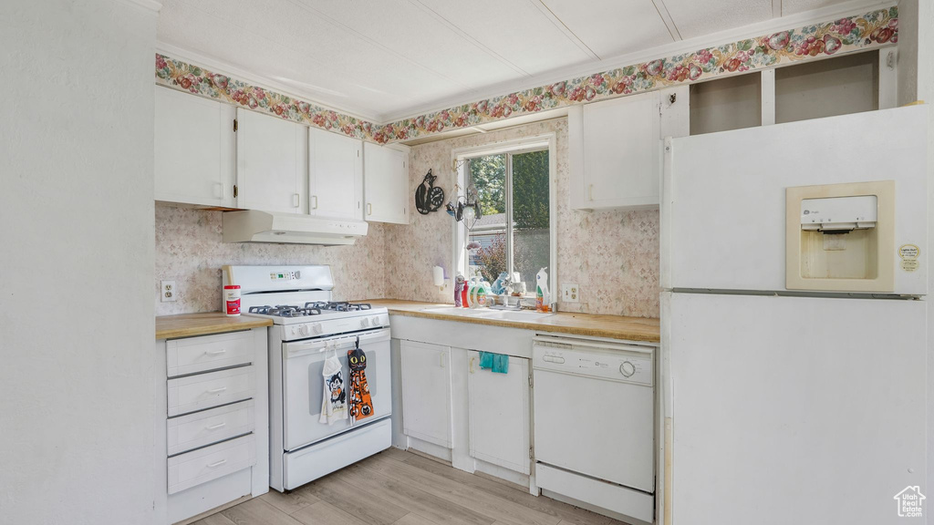 Kitchen featuring white appliances, premium range hood, light countertops, white cabinetry, and light wood-style floors