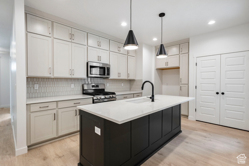 Kitchen featuring stainless steel appliances, light wood-style flooring, backsplash, light countertops, and recessed lighting