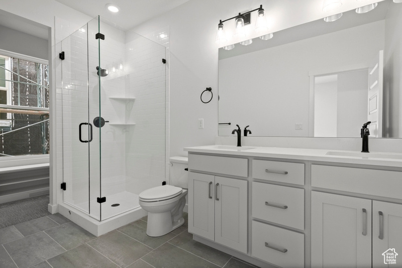 Bathroom with double vanity, a shower stall, and tile patterned floors