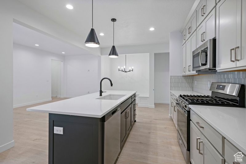 Kitchen featuring appliances with stainless steel finishes, light wood-type flooring, light countertops, a chandelier, and recessed lighting