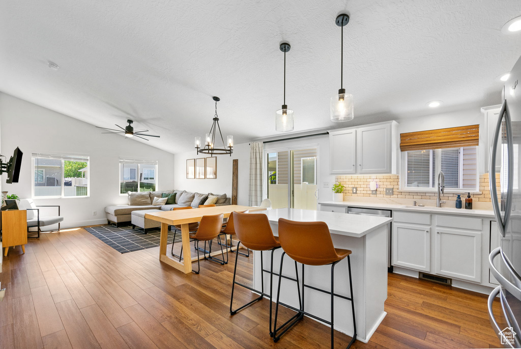 Kitchen featuring decorative backsplash, white cabinets, a kitchen bar, light countertops, and ceiling fan
