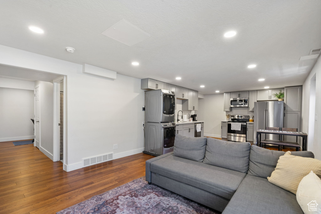 Living room featuring estacked washer and dryer, dark wood-type flooring, and recessed lighting
