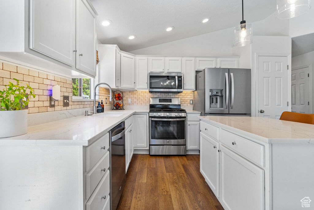 Kitchen featuring stainless steel appliances, dark wood finished floors, white cabinetry, recessed lighting, and lofted ceiling