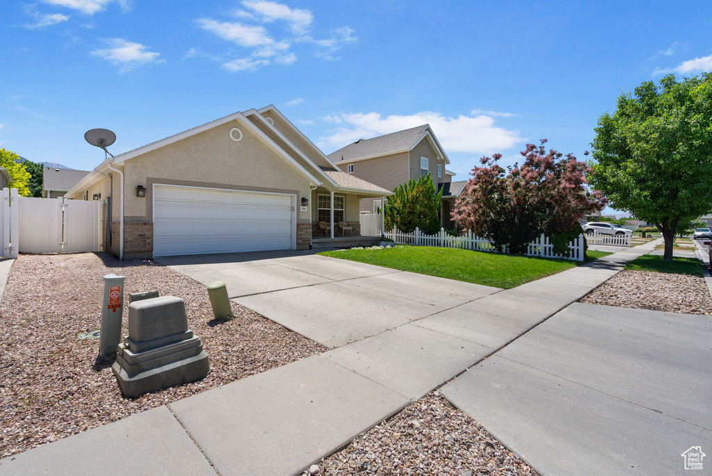 View of front of property featuring a garage, driveway, stucco siding, and a gate