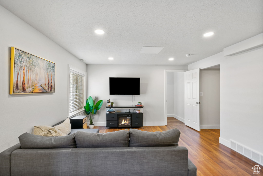 Living area with wood finished floors, recessed lighting, and a textured ceiling