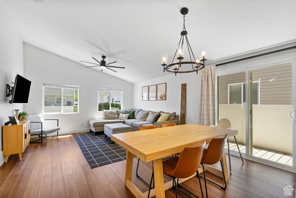 Dining room with a chandelier, vaulted ceiling, a ceiling fan, and dark wood-style flooring