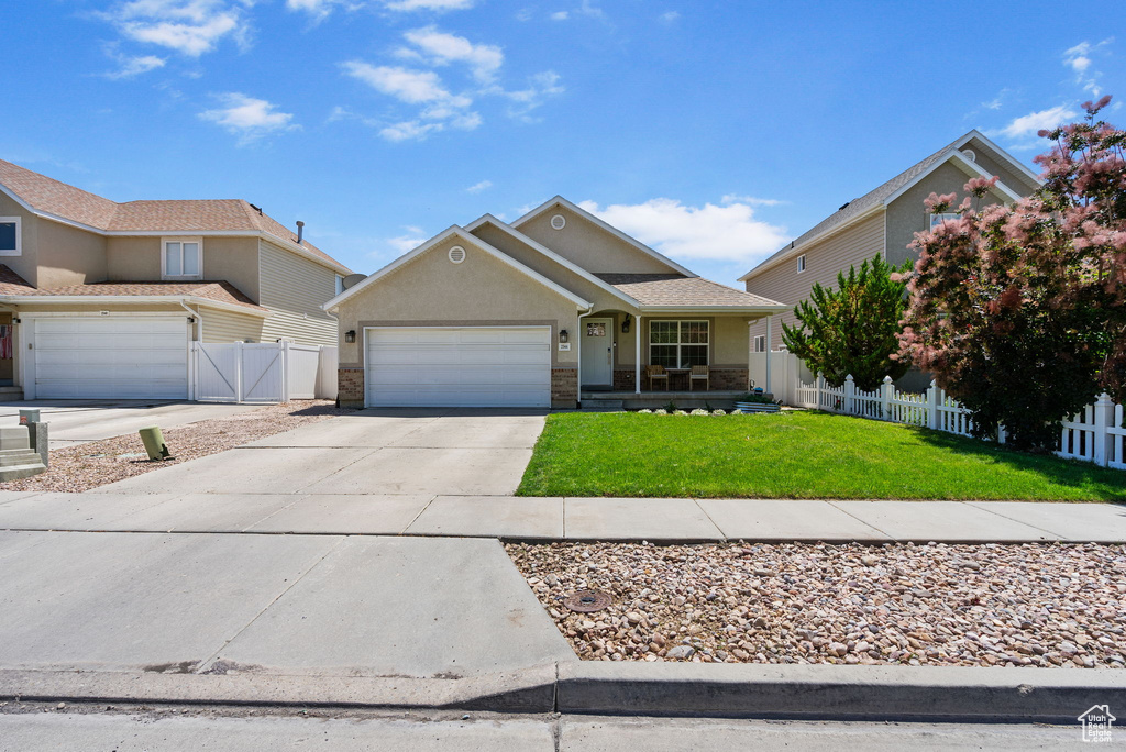 View of front of property featuring an attached garage, concrete driveway, stucco siding, and covered porch