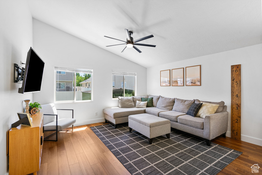 Living area with vaulted ceiling, ceiling fan, and dark wood-style flooring