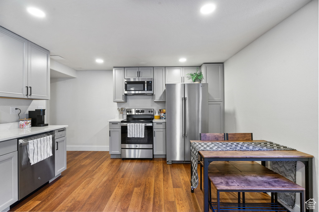 Kitchen featuring appliances with stainless steel finishes, gray cabinets, light countertops, dark wood-type flooring, and recessed lighting