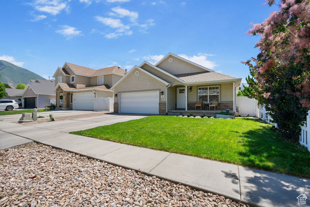View of front of home with covered porch, driveway, an attached garage, stucco siding, and stone siding