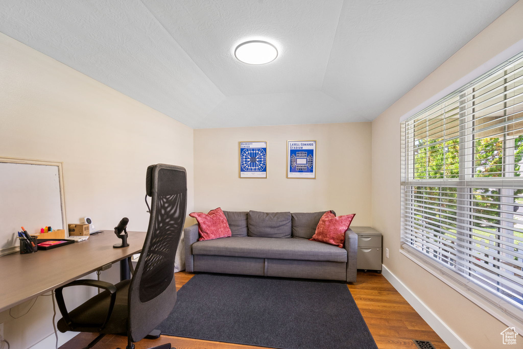 Office space with wood finished floors and a raised ceiling