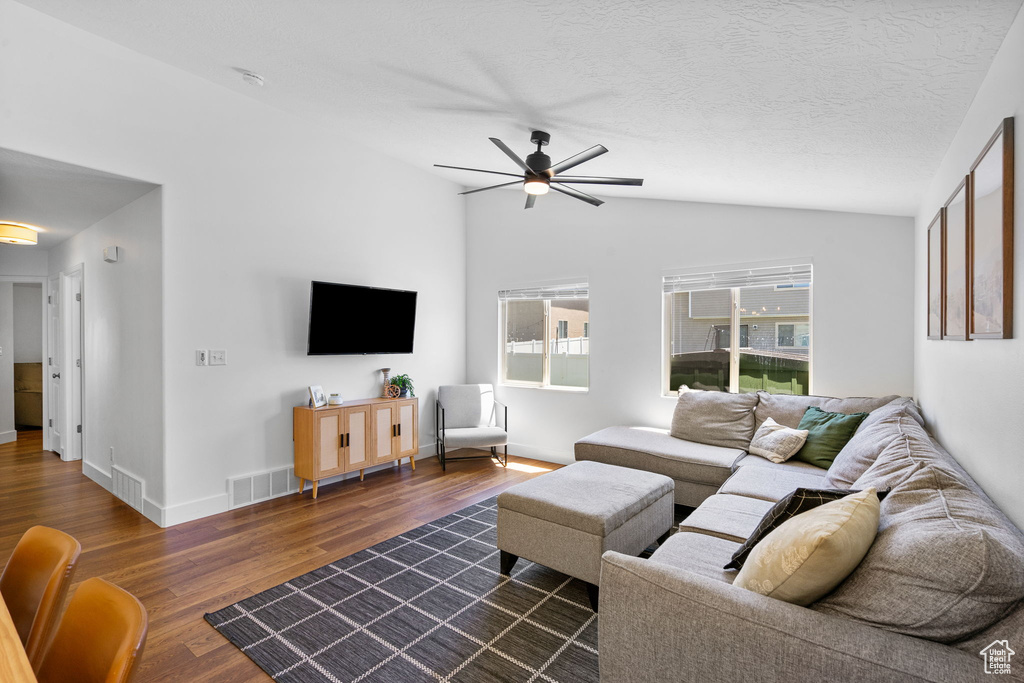 Living room with lofted ceiling, ceiling fan, and dark wood-style floors